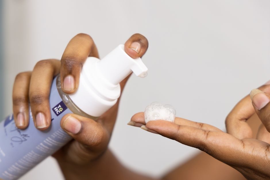 A foaming facial cleanser being pumped into a hand