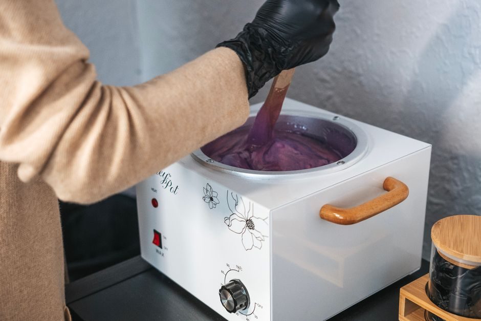 A wax warmer with purple wax being stirred